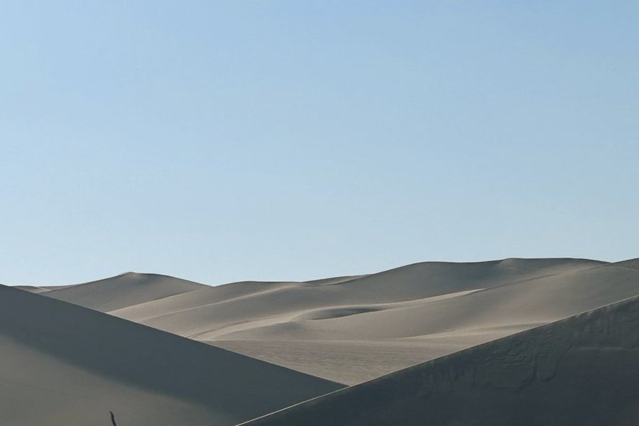 Sweeping sand dunes under a clear pale sky, Peru