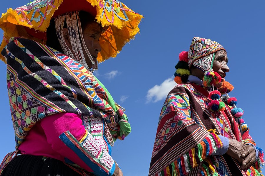 Two elders in colourful traditional Andean dress against blue sky